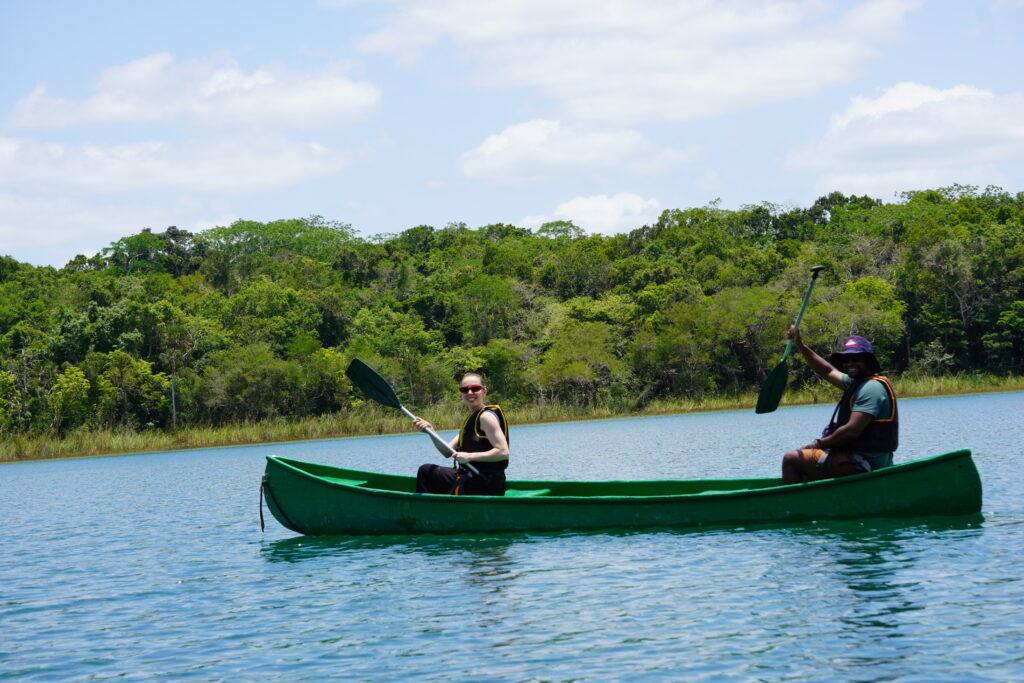 Two travelers paddling a canoe across a jungle lagoon