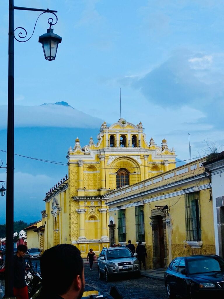 Yellow church of La Merced in Antigua Guatemala with a volcano behind
