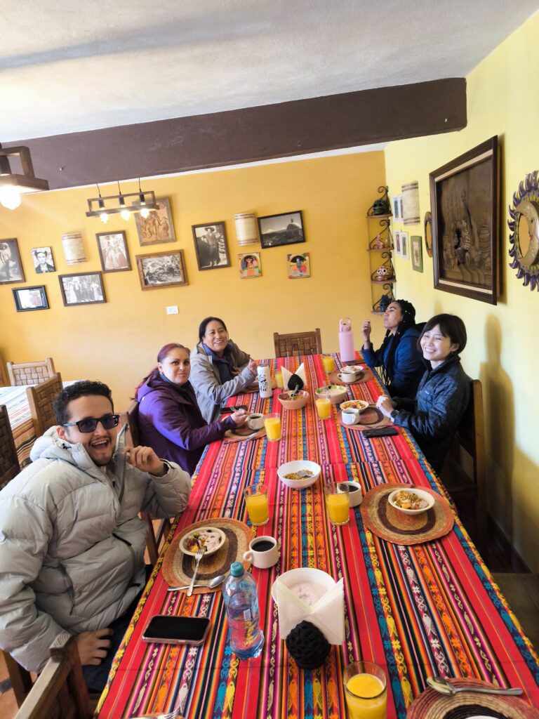 Grupo de viajeros de Odyssey desayunando juntos en una mesa con textil tradicional
