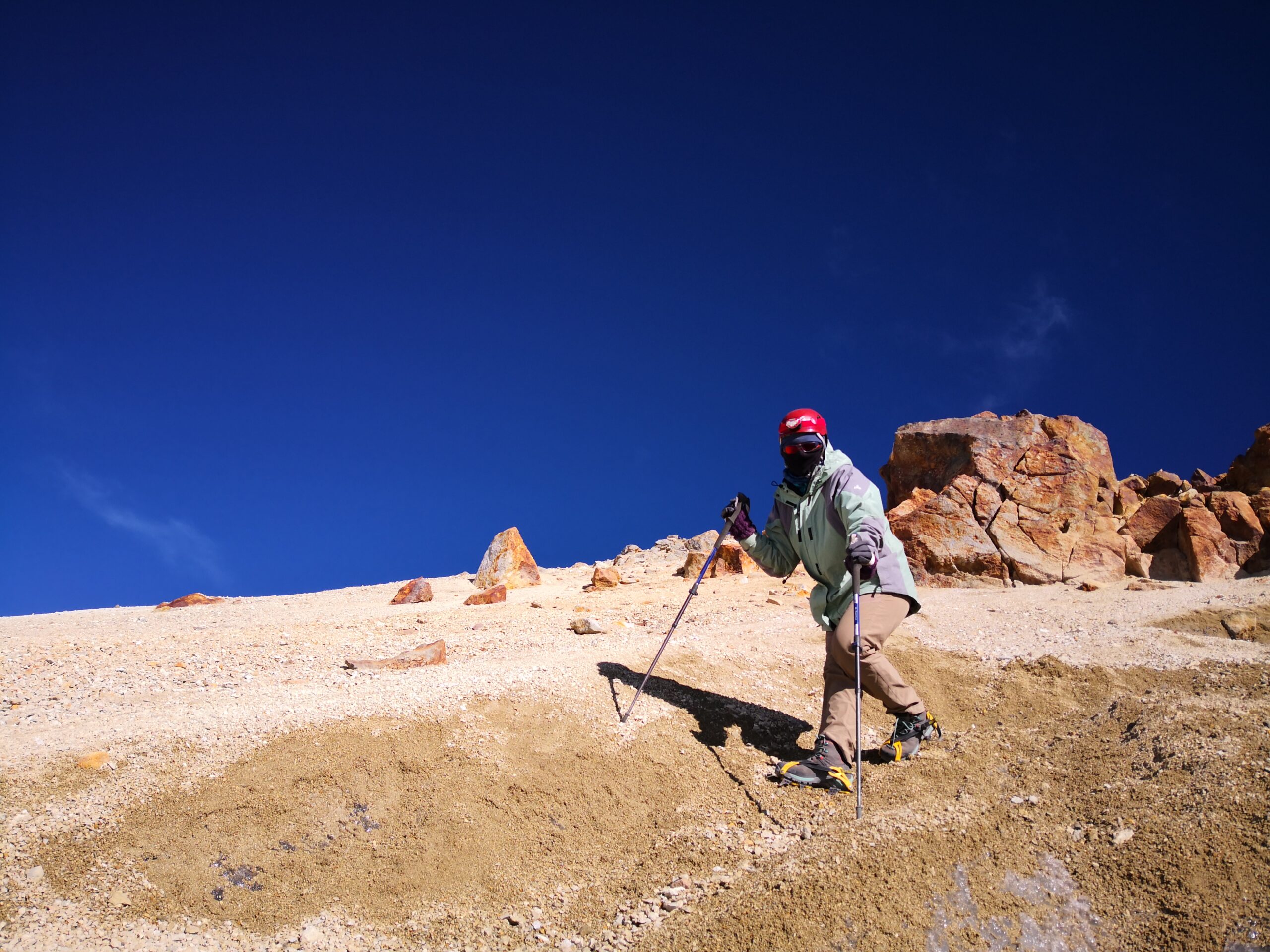 Climber with trekking poles on the Iztaccíhuatl ridge under a deep blue sky