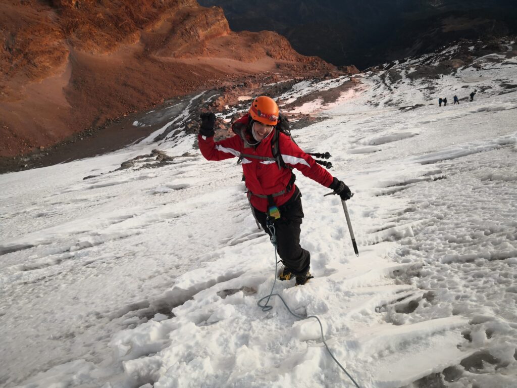 Climber with helmet and ice axe on the snow of Pico de Orizaba at sunrise